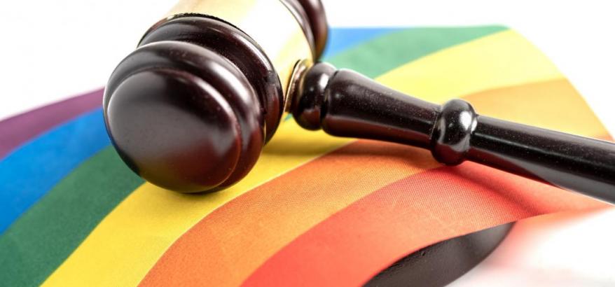 Martelo, símboilo do Judiciário, repousa sobre uma bandeira do arco-íris, símbolo do movimento LGBTQIAP+ 