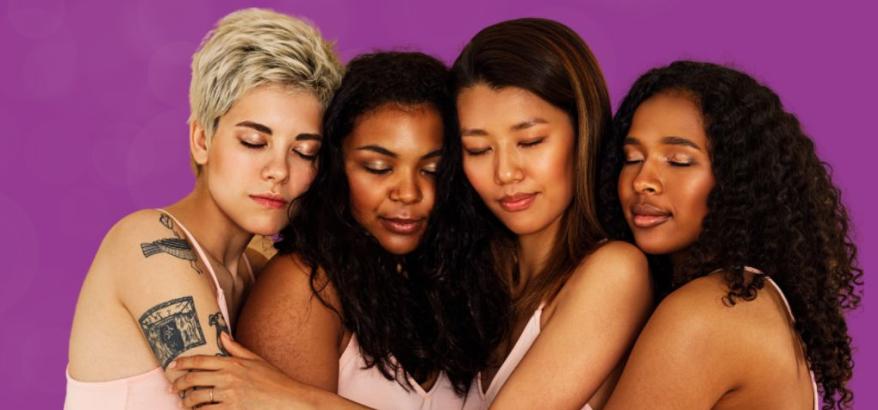 quatro mulheres de etnias diversas abraçadas e de olhos fechados