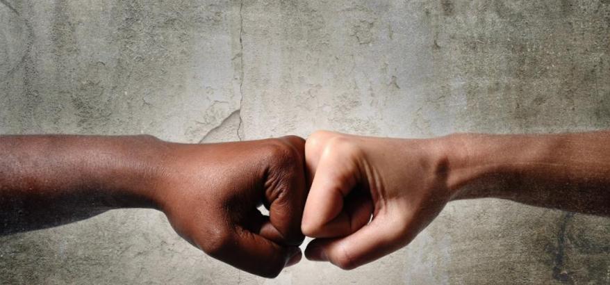 Duas mãos se encontrando, de uma pessoa branco e outra negra. Abaixo, o seguinte título: "Núcleo de conciliação do TRF2 divulga relatório do 1º trimestre: proferidas quase 6 mil sentenças homologando acordos"